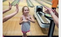 A Summer Reading participant prepares to high five her team at Torresdale Library's 10th annual Read, Eat, and Bowl.